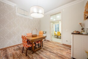 A dining area with a wooden table, patterned chairs, and a hanging light fixture. - GuestReady - Stay in the Heart of Lisbon (Lisbon)