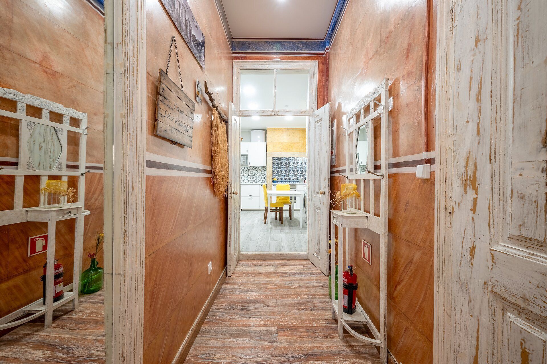 Un couloir étroit aux murs en bois, doté d’un sol carrelé et d’une porte donnant sur un espace cuisine.
