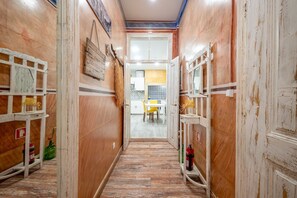 A narrow hallway with wooden walls, a tiled floor, and a door leading to a kitchen area. - GuestReady - Stay in the Heart of Lisbon (Lisbon)