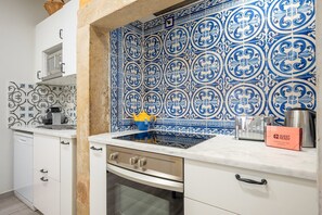 Une cuisine avec un plan de travail blanc, un pare-feu bleu et blanc à motifs, et une hotte de cuisinière en acier inoxydable.