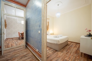 A hotel room with a bed, a bedside table, a chair, and a door leading to another room. - GuestReady - Stay in the Heart of Lisbon (Lisbon)