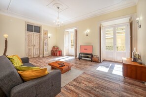 Un salon avec un canapé, une table basse, un téléviseur et un lustre.
