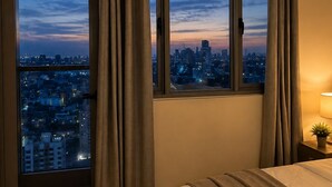 Quarto de hotel com vista para a cidade, uma cama, mesa de cabeceira e cortinas.