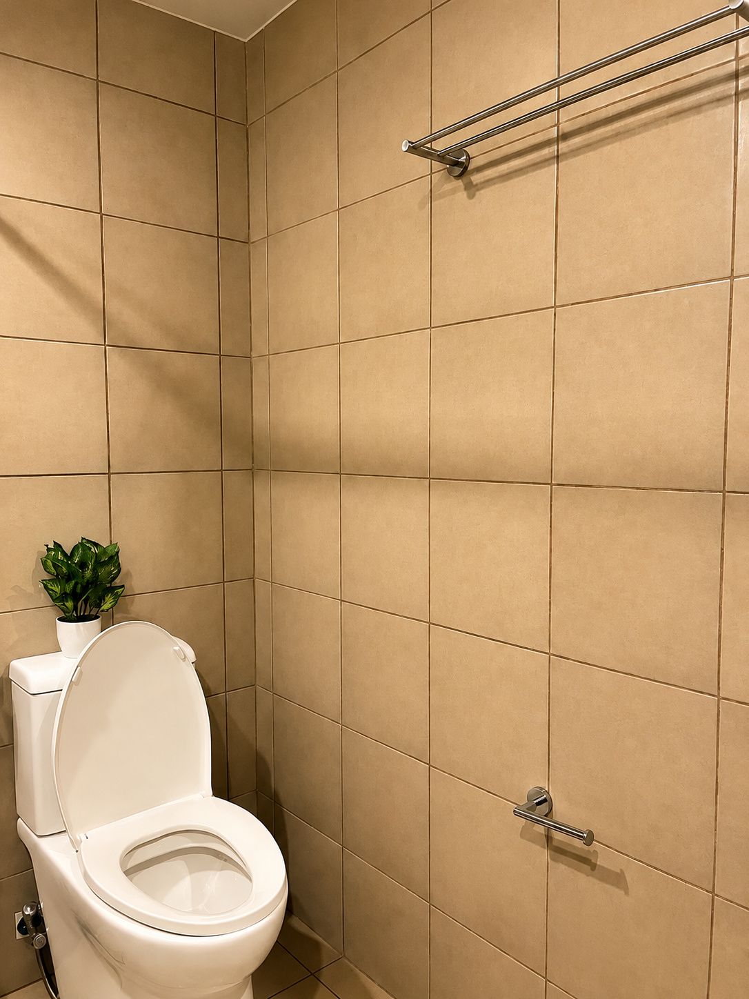A bathroom with a toilet, a towel rack, and a potted plant.