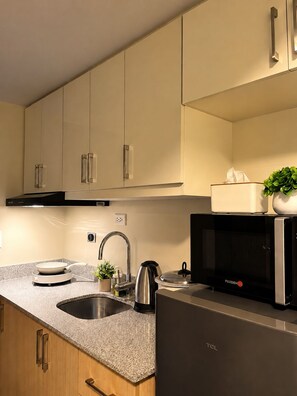 Een moderne keuken met een spoelbak, fornuis, magnetron en kastjes.