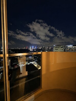 Une vue nocturne sur la ville, prise depuis un immeuble de grande hauteur, avec un ciel dégagé et des nuages.