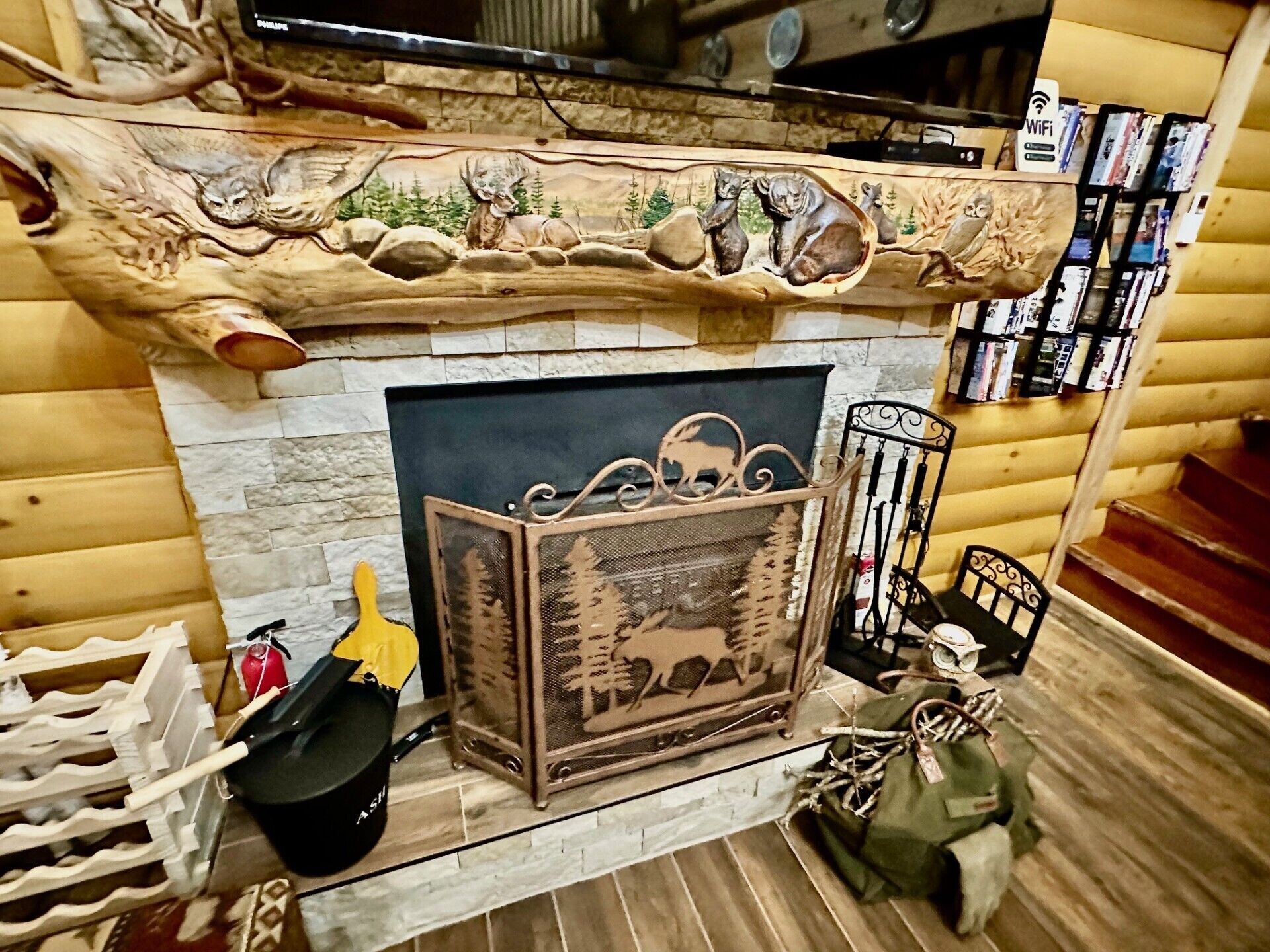 A fireplace with a carved mantelpiece, a metal grate, and a small shelf with books and a decorative item.