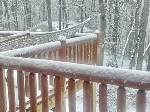 A wooden balcony railing with snow accumulation, overlooking a traditional building with a tiled roof, set in a snowy forest. - A Custom-Built Swiss-Style Luxury Mountain Retreat - Entire 5 BR Chalet (Mount Jackson)