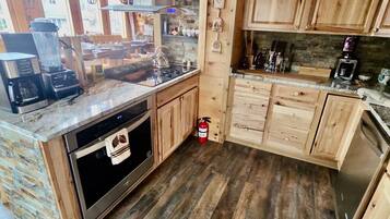 Uma cozinha com armários de madeira, forno embutido, cafeteira e extintor de incêndio.