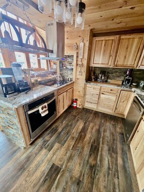A kitchen with wooden cabinets, a built-in oven, a coffee maker, and a fire extinguisher.