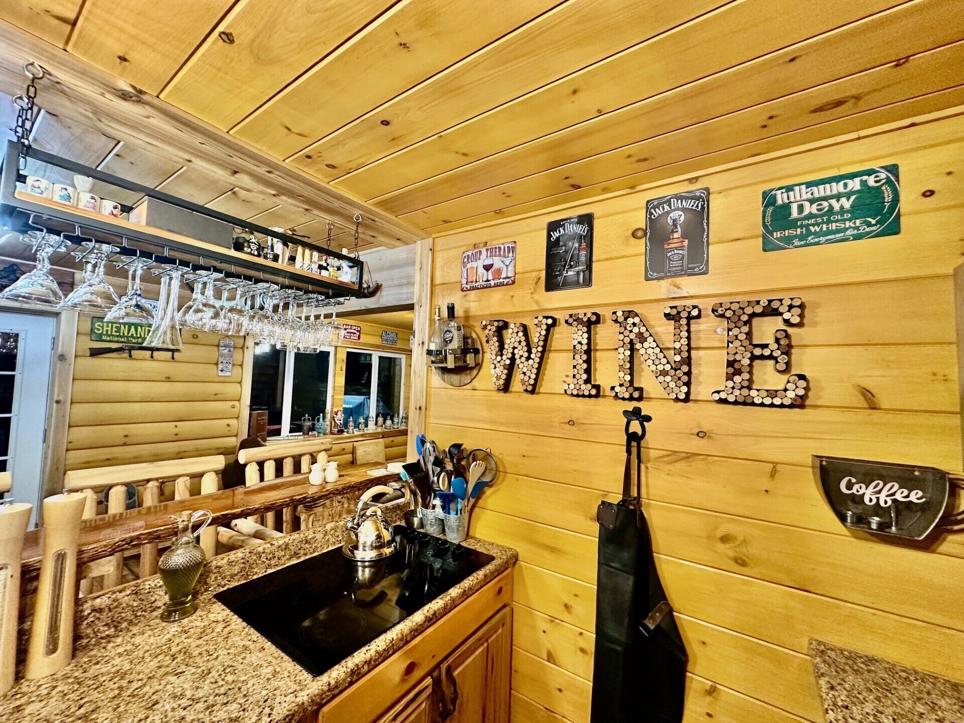 A bar area with wooden walls, a wine sign, and various liquor bottles.