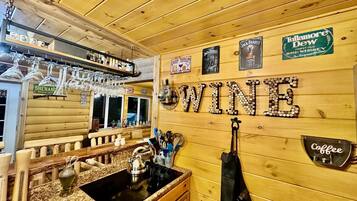A bar area with wooden walls, a wine sign, and various liquor bottles.