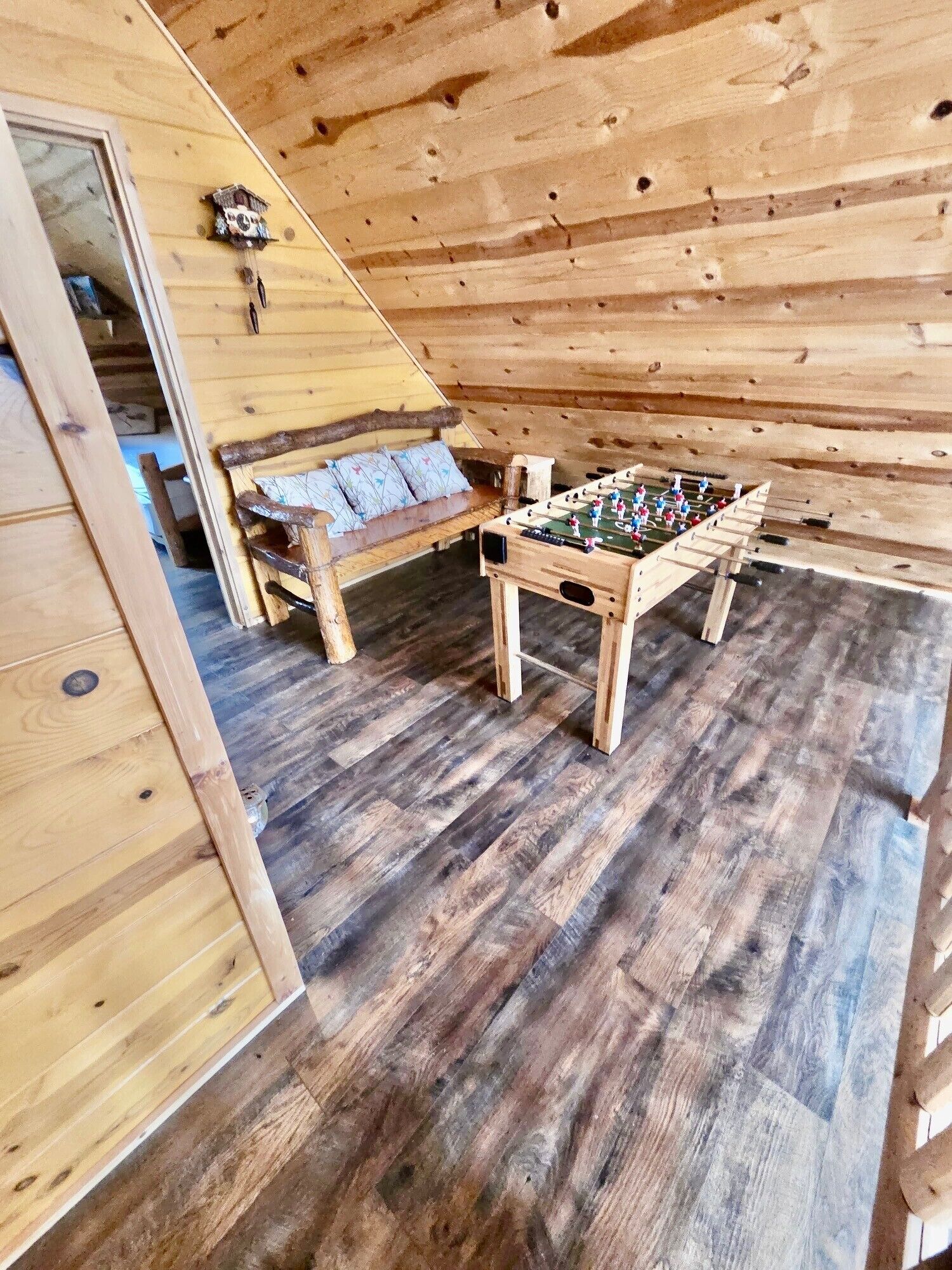 A wooden-floored room with a sofa and a foosball table.