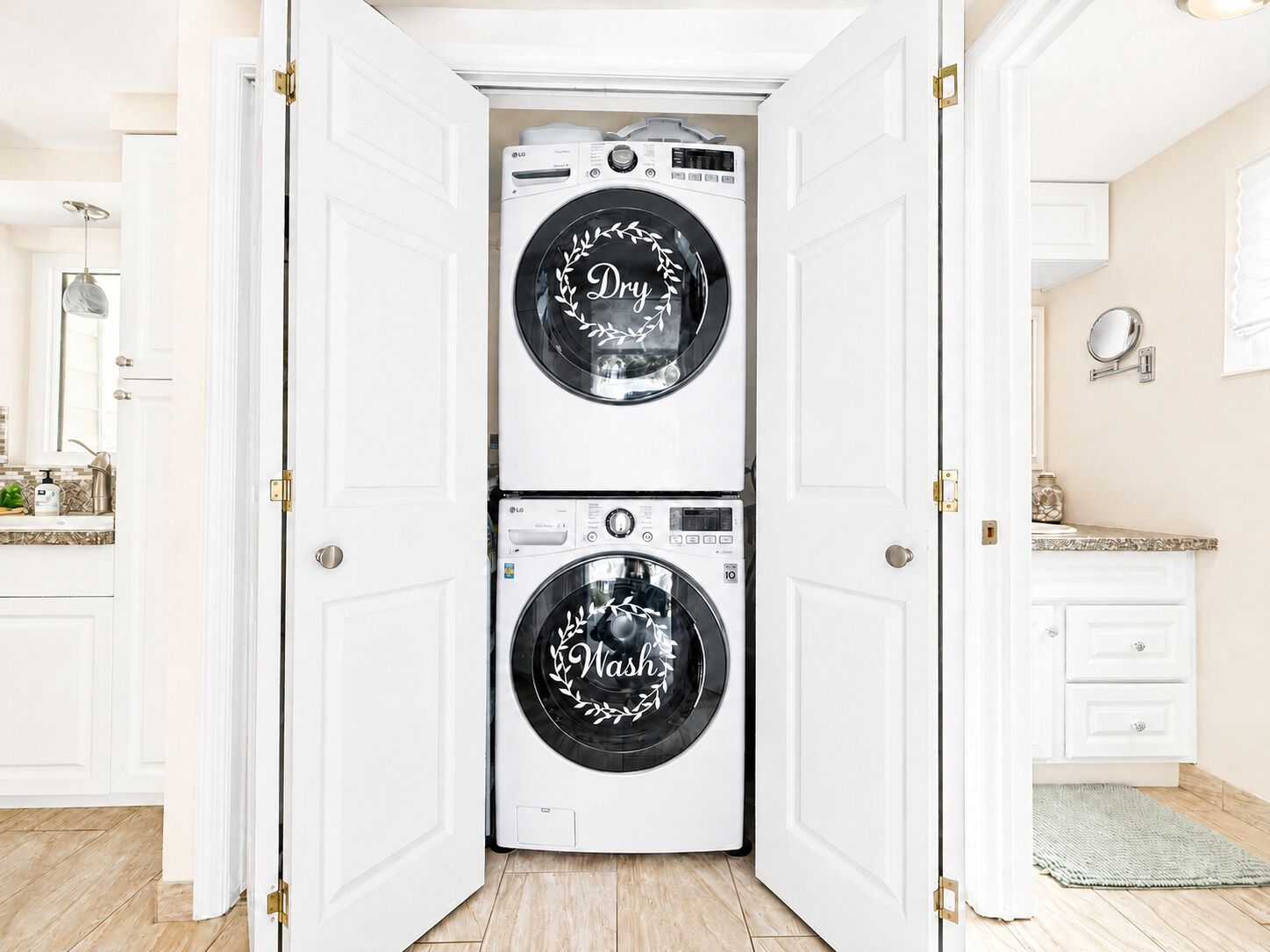 A laundry room with two stacked front-loading washing machines, a mirror, and a sink.
