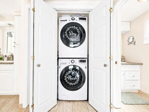 A laundry room with two stacked front-loading washing machines, a mirror, and a sink. - Pool & Hot Tub near Siesta Key Beach (Sarasota)