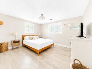Een slaapkamer met een bed, nachtkastjes, een televisie en een raam.