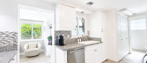 A modern kitchen with white cabinetry, a stainless steel dishwasher, and a patterned backsplash.