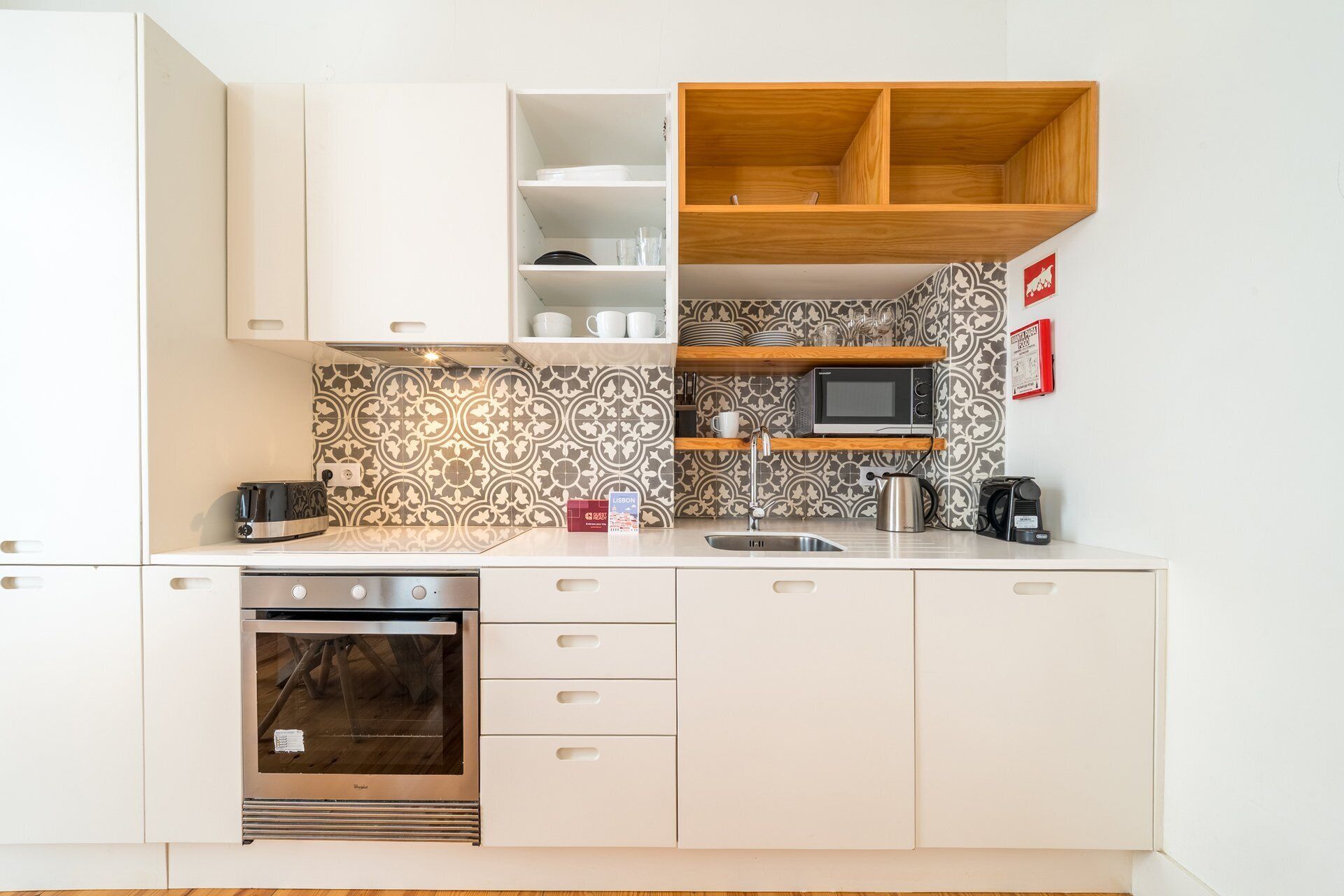 A compact kitchen with white cabinetry, a microwave, a coffee maker, and a toaster.