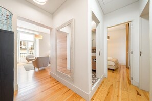Een modern interieur met een houten vloer, een grote spiegel en een eethoek met een stoel en tafel.
