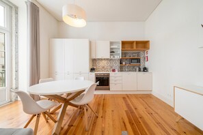 A modern kitchen with white cabinetry, a round dining table with chairs, and a wooden floor. - GuestReady - Great stay near Lisbon Cathedral (Lisbon)