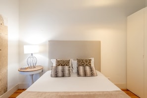Ein Hotelzimmer mit einem Bett, einem Nachttisch mit Lampe und einer Wand mit strukturierter Oberfläche.