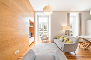Ein modernes Wohnzimmer mit einer Couch, einem Sessel, einem Esstisch und einer Lampe.
