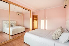 A bedroom with a large mirror, a bed with white bedding, and a wooden floor. - GuestReady - Carnaxide elegant villa with 2 pools (Carnaxide)
