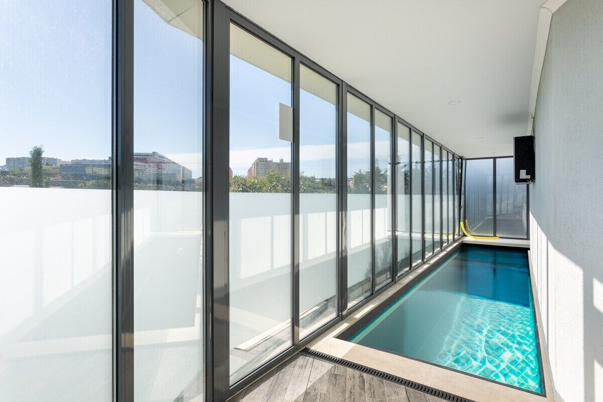 Una piscina interior moderna con amplios ventanales y vistas a la ciudad.