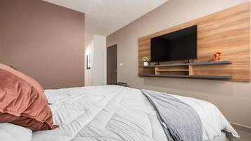 A bedroom with a bed, a mounted TV, and a door.