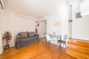 A compact living space with a sofa, dining table, chairs, a potted plant, and a fire extinguisher. - GuestReady - Brilliant stay near São Jorge Castle (Lisbon)