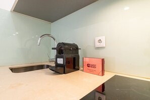 Ein Küchenbereich mit Spüle, einer Kaffeemaschine und einer roten Kiste mit dem Aufdruck 'GUEST READY'.