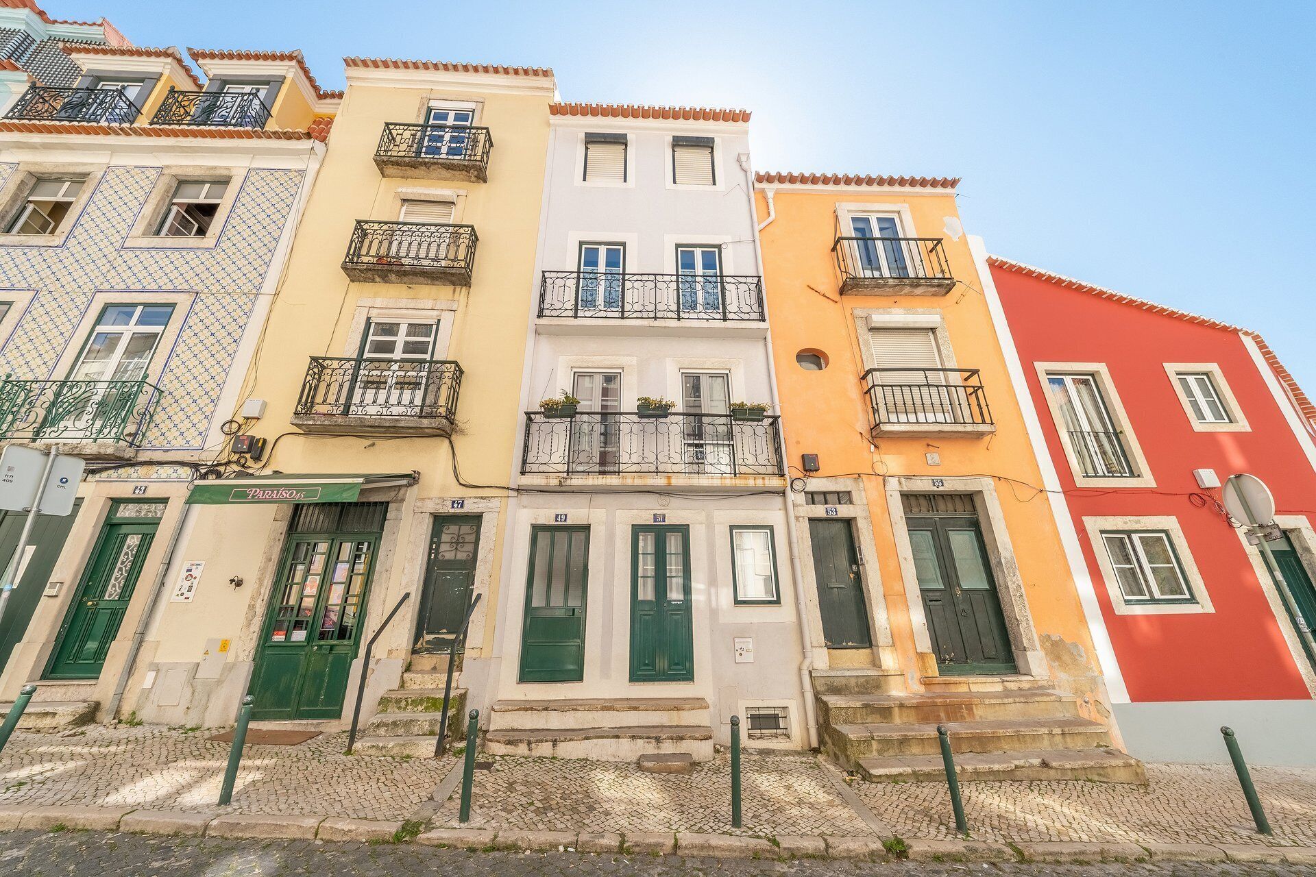 A row of colorful buildings with balconies and green doors.