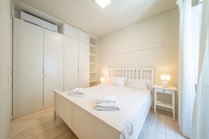 Ein Schlafzimmer mit einem Bett, Nachttischen, einem Kleiderschrank und einer Deckenleuchte.