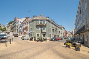 A street view with multi-story buildings, parked cars, and a clear sky. - GuestReady - Bold escape near Jardim da Estrela (Lisbon)