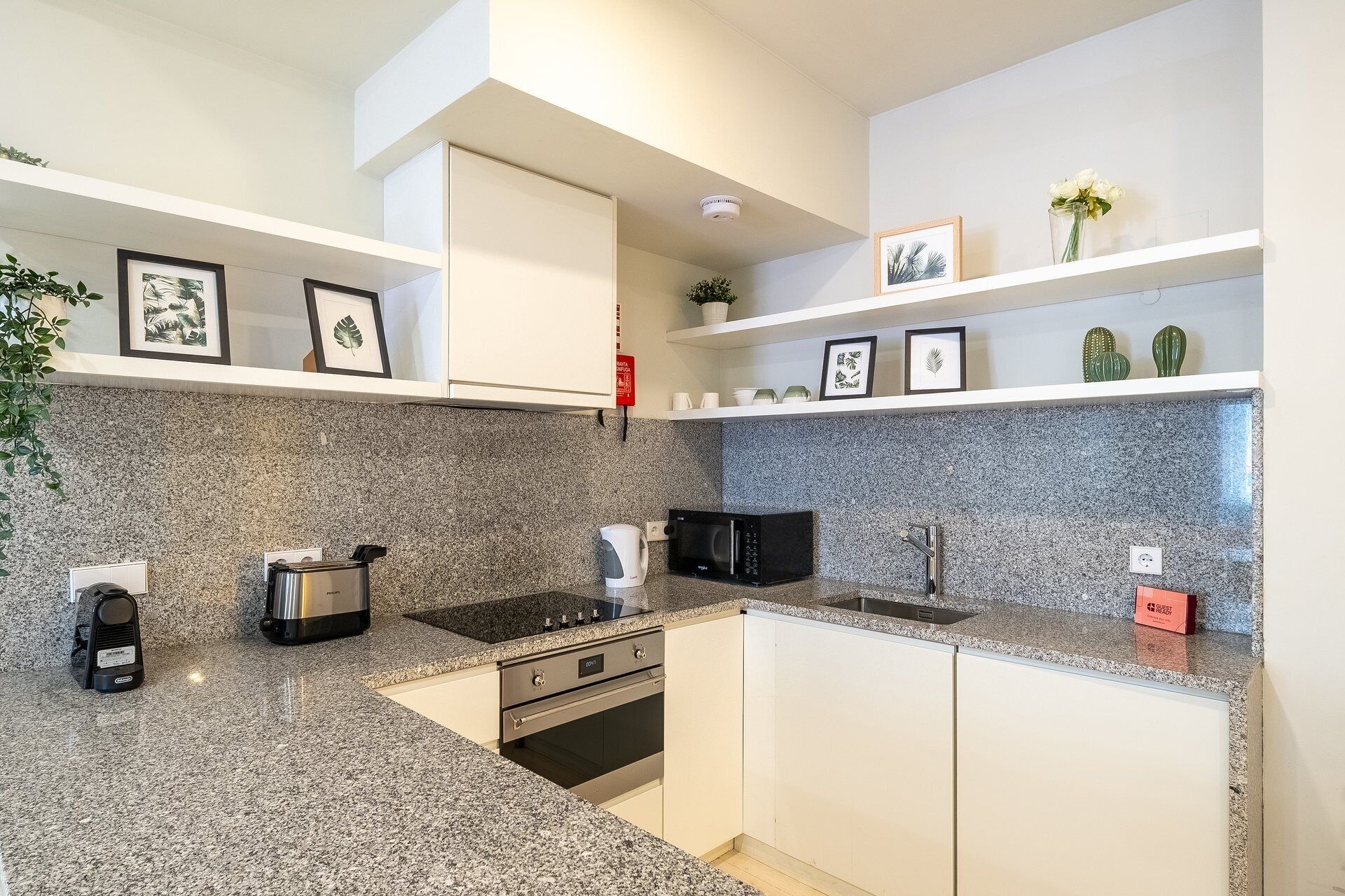 Una cocina moderna con encimeras de granito, electrodomésticos de acero inoxidable y armarios blancos.