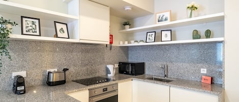 A modern kitchen with granite countertops, stainless steel appliances, and white cabinetry.