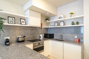 Eine moderne Küche mit Granit-Arbeitsplatten, Edelstahlgeräten und weißen Schränken.