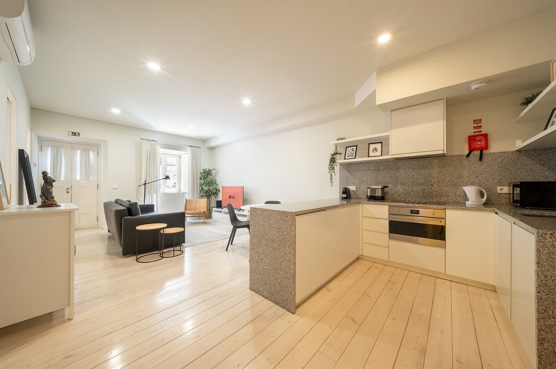 A modern kitchen with granite countertops, a built-in oven, and a dining area with a sofa and chairs.