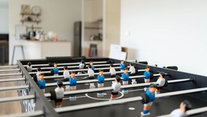 Een tafelvoetbaltafel in een kamer, met een keuken op de achtergrond.