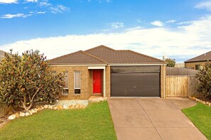 A residential house with a red door, a garage, and a well-maintained lawn.