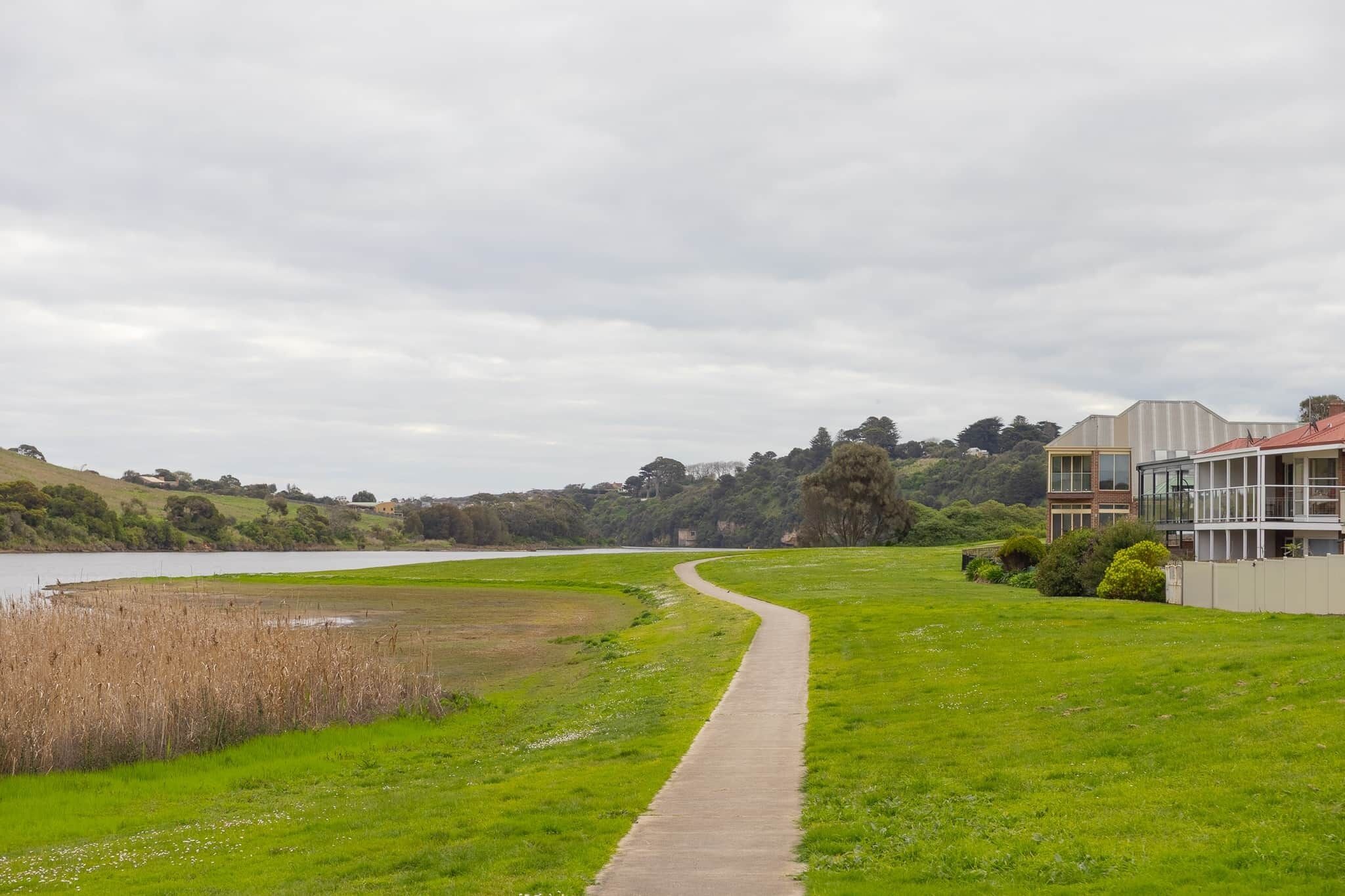 A pathway leading to a building with a view of a lake and hills.