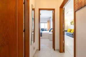 A hallway leading to a bedroom with a bed, a desk, and a window. - GuestReady - Deluxe home with terrace in Caparica (Almada)