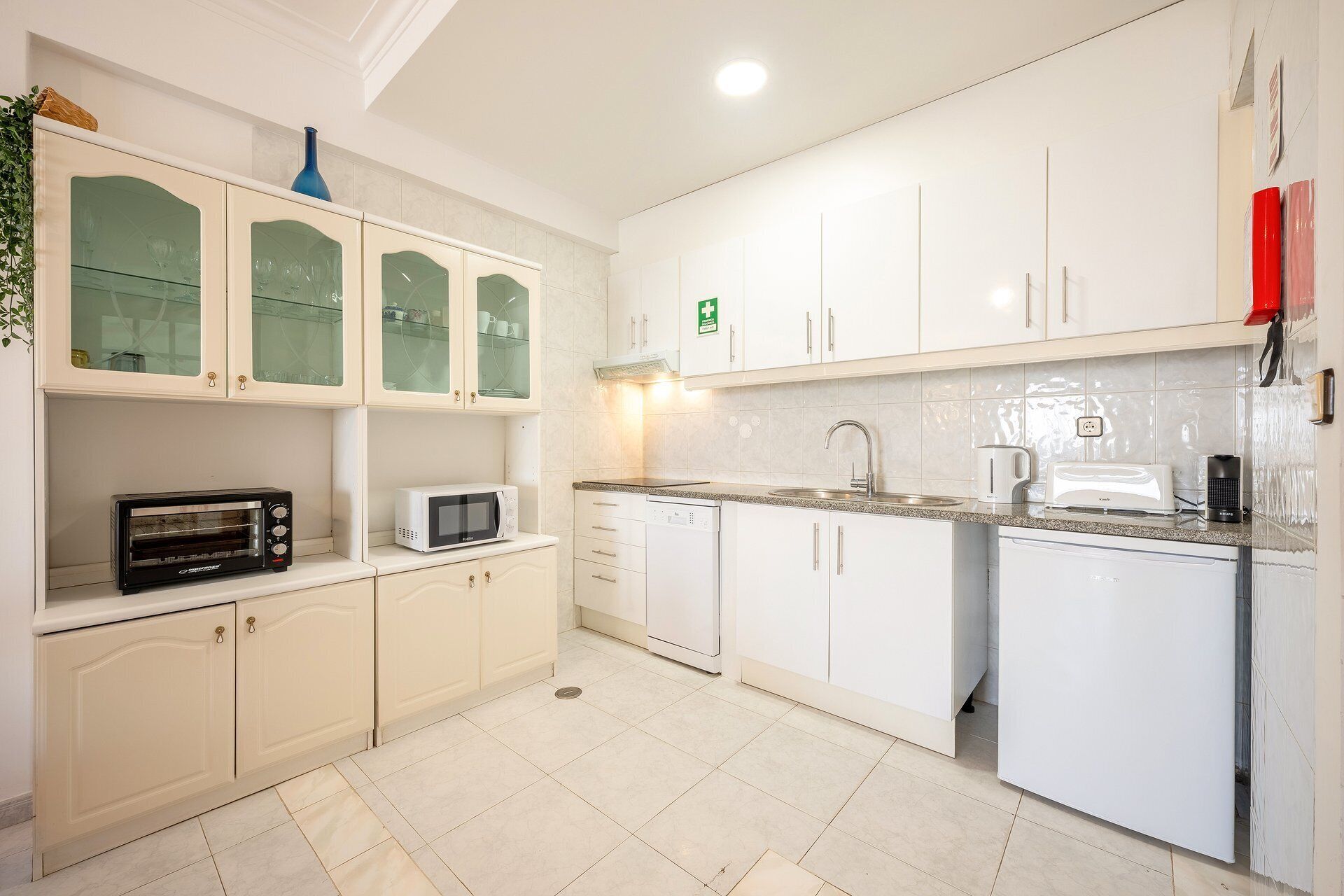 Una cocina moderna con armarios blancos, un microondas, un tostador y un lavamanos.