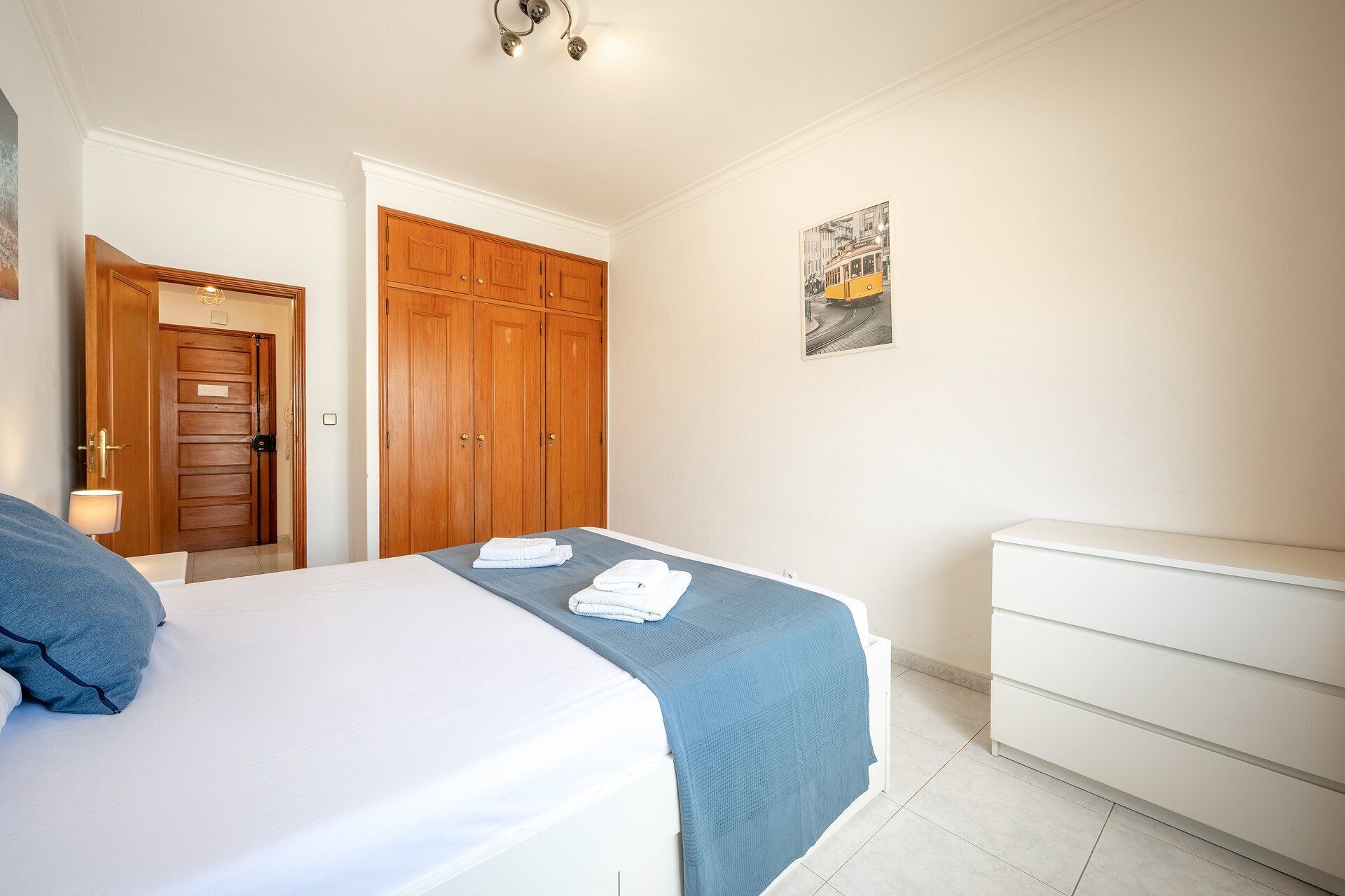 Une chambre à coucher comprenant un lit, une armoire, une table de chevet et un tableau accroché au mur.