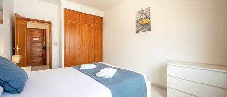 Un dormitorio con cama, armario, mesita de noche y un cuadro colgado en la pared.