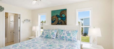 A bedroom with a bed, two bedside tables, a ceiling fan, a window, and a door.