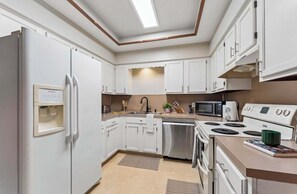 A modern kitchen with white cabinets, a built-in microwave, a stove, and a refrigerator.