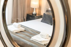 Une chambre d’hôtel avec un lit, des oreillers, une table de chevet, une lampe et des serviettes.