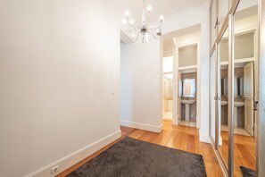 Un couloir agrémenté d’un lustre, doté d’un plancher en bois et recouvert d’un tapis foncé.