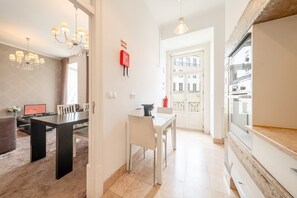 A modern kitchen with a built-in oven, a dining area with a table and chairs, and a chandelier. - GuestReady - Elegant Central Home with Terrace (Lisbon)